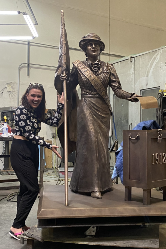 Sculptor Stephanie Hunter standing beside her bronze statue of Frances Willard Munds in the Bollinger Atelier warehouse.