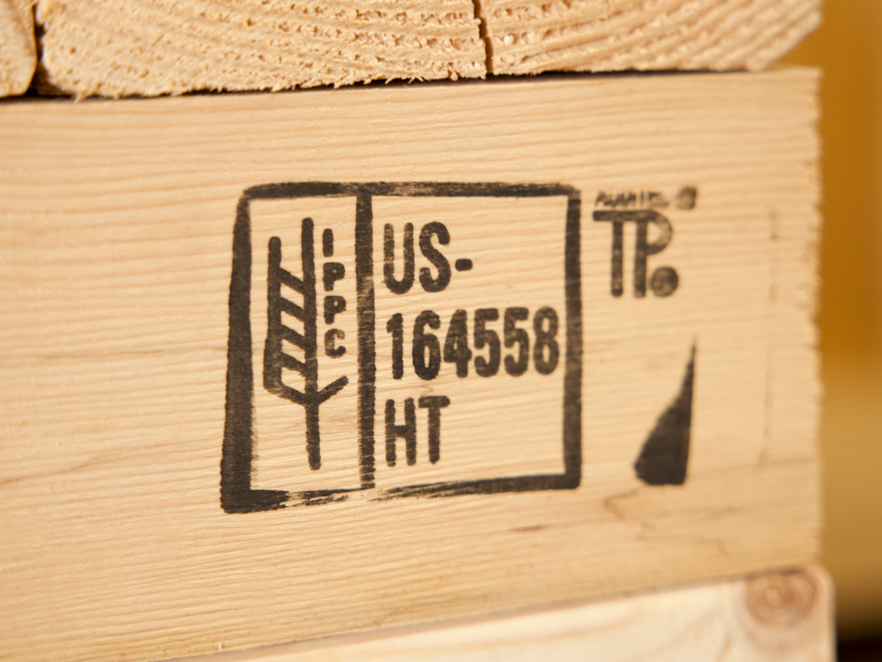 Close-up of the ISPM-15 stamp on a wooden crate, showcasing compliance with international shipping regulations for treated wood packaging