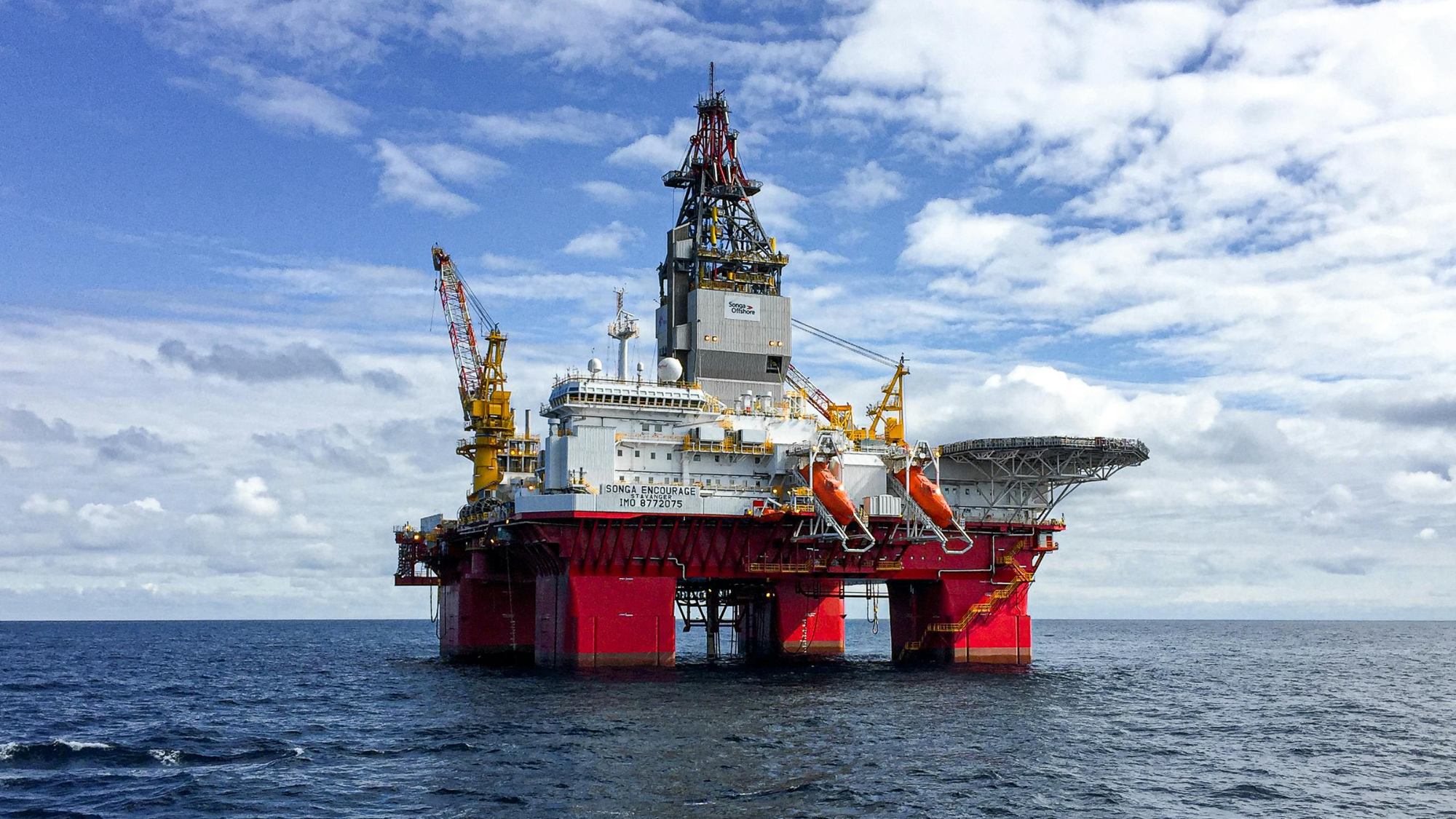 Offshore oil rig at sea with support structures and drilling towers under cloudy sky