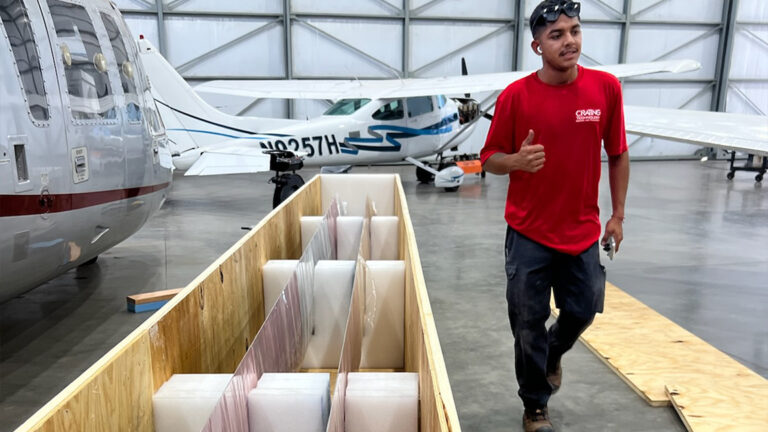 Helicopter blades secured inside a custom wood crate with foam-lined cradles for protection against movement and impact.