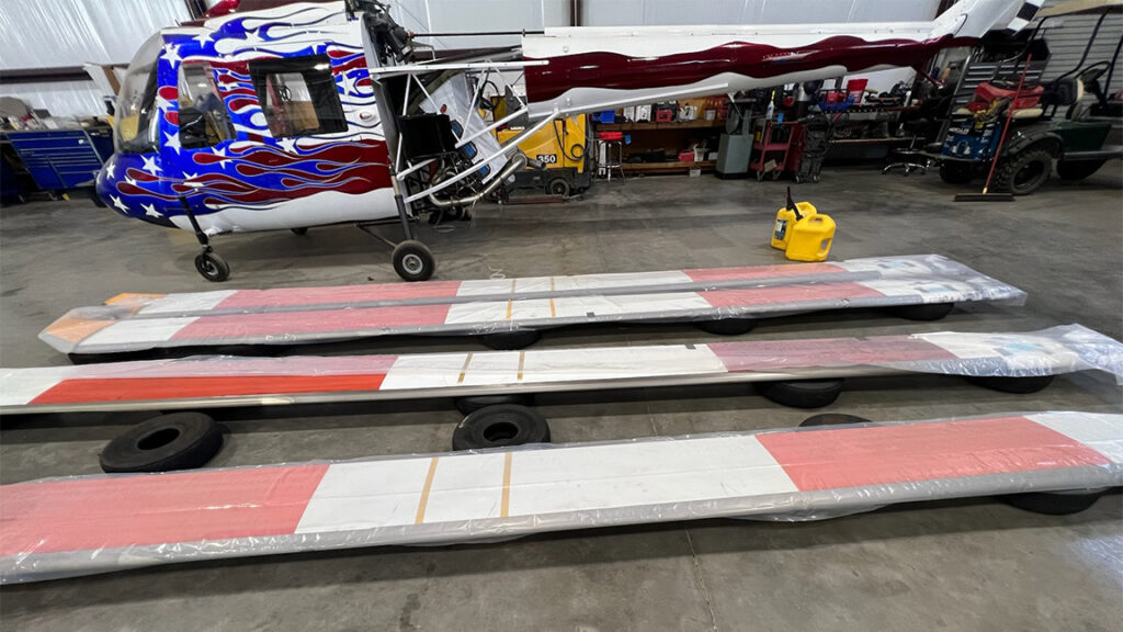 Helicopter blades resting on the hangar floor before being crated for secure handling and transport.