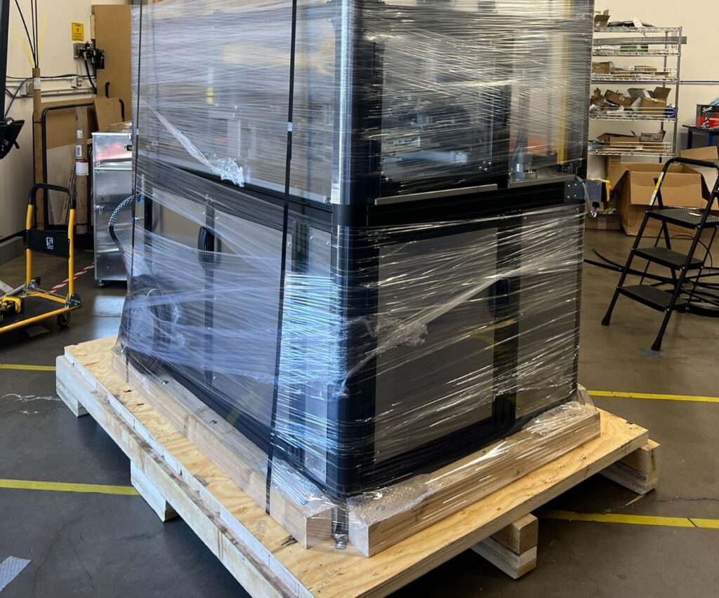 Shrink-wrapped industrial machine secured on a custom wooden skid